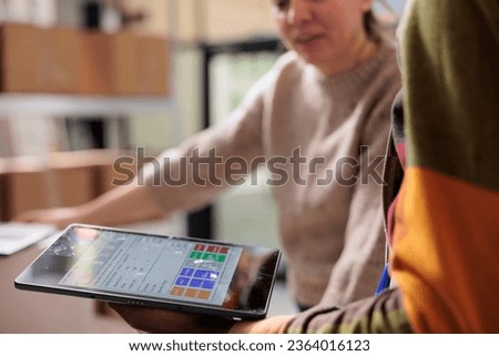 Stockroom team analyzing online orders on tablet computer, preparing packages for delivery in warehouse. Diverse employees working at goods inventory, typing report on digital device