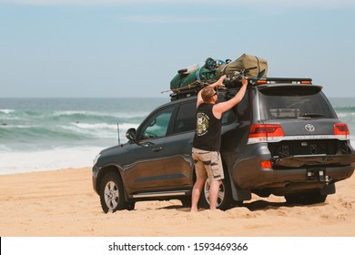 Stockton Beach, New South Wales / Australia - October 2 2017: Man Checking Luggage On The Roof Rack Of His Four Wheel Drive On The Beach. Sand Driving, Off Roading. 