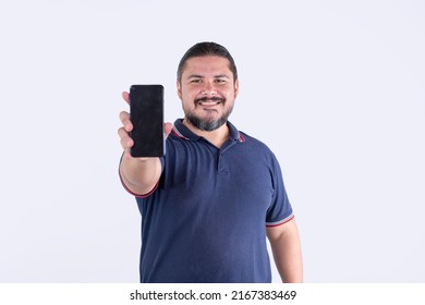 A stocky, beared man of mixed race and in his 30s shows his cellphone. Isolated on a white backdrop. Communications concept.