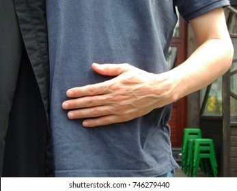 Stomach Ache Or Hungry Feeling, The Man Touch His Stomach Which Cover With Gray Shirt With His Left Hand.