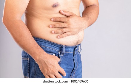 Stomach Ache Or Pain On Belly Concept : Fat Man Using His Hand And Pressing On Stomach On Grey Background