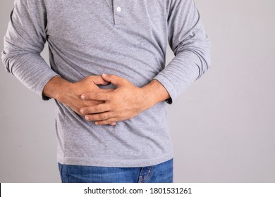 Stomach Ache Or Pain On Belly Concept : Fat Man Using His Hand And Pressing On Stomach On Grey Background