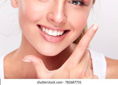 Stomatology concept, partial portrait of girl with strong white teeth looking at camera and smiling, fingers near face. Closeup of young woman at dentist's, studio, indoors - Shutterstock ID 782687731