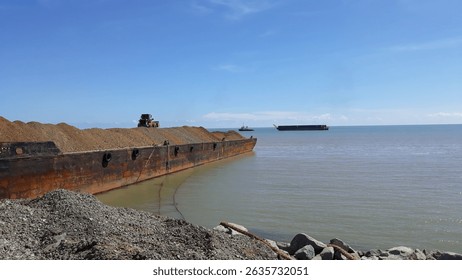 Stone aggregate loading process on the steel barge or scow at jetty