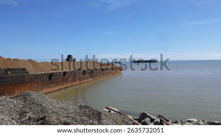 Stone aggregate loading process on the steel barge or scow at jetty