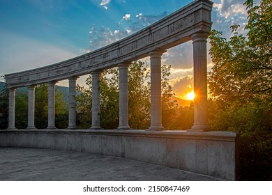 Stone ancient colonnade against the blue sky and green forest illuminated with sunset light in Dilijan, Armenia