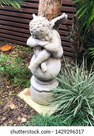 Stone Angel Or Cherubim Statue In A Garden With Plants