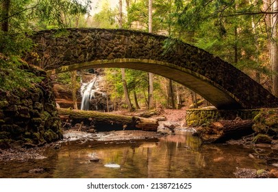 Stone arch bridge in the forest. Old arched bridge over forest river stream. River bridge in forest. Arched stone bridge