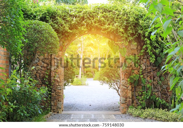 Stone arch entrance gate archway to the park with sunlight.