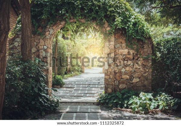 Stone arch\
entrance wall with ivy in the\
garden.\
