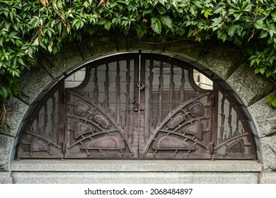 A stone arch with an old metal grating with a padlock. Metal gates built into the arched doorway.