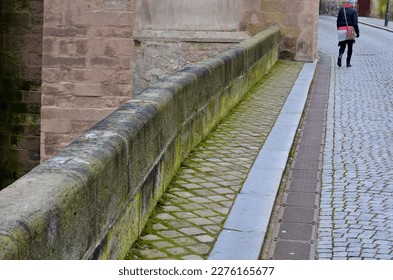 stone balustrade the bridge at the church made worked sandstone blocks and rounded edge  along the paved road is metal grid longitudinal gutter for rainwater