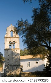 The stone belltower of agios constantinos surrounded by olive trees, paxos, ionian islands, greek islands, greece, europe