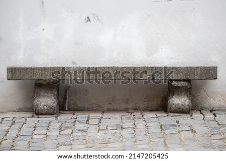 Stone bench with old wall on background and cobblestone on street