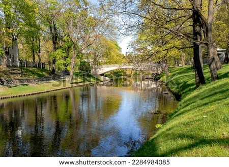 Stone bridge over Riga river canal in Riga central city park at sunny spring day, capital of Latvia. 