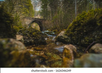 Stone bridge at the river spring of Kamniska Bistrica in Slovenia in dry winter time. Cold enchanted bridge with flowing water underneath in the middle of the forest.