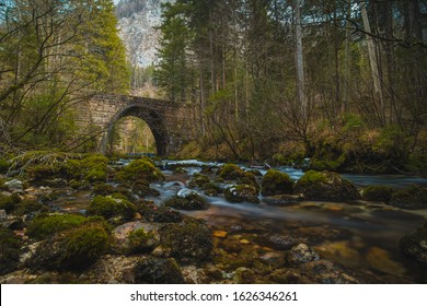 Stone bridge at the river spring of Kamniska Bistrica in Slovenia in dry winter time. Cold enchanted bridge with flowing water underneath in the middle of the forest.