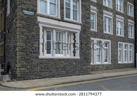 Stone Building Facade With White Framed Windows Along Quiet Urban Welsh Street