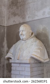 Stone Bust Of A Monk On A White Brick Pedastal