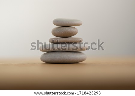 Stone cairn on striped grey white background, five stones tower, simple poise stones, simplicity harmony and balance, rock zen sculpture