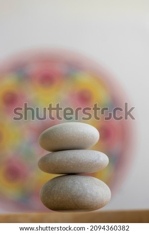 Stone cairn on white and colorfull red yellow mandala background, three stones tower, simple poise stones, simplicity harmony and balance, rock zen sculpture
