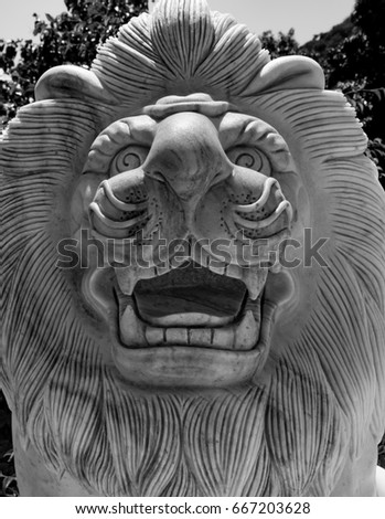 Stone calving of lions head and face with its mane in black and white.