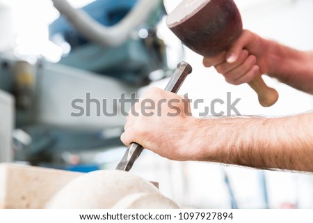 Stone carver working with hammer and chisel at marble column
