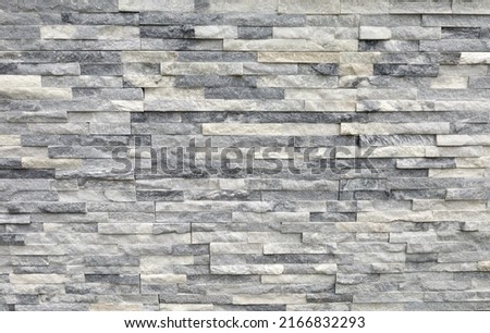 Stone cladding wall made of regular  bricks of white, gray and black rocks. Panels for exterior, background and texture.