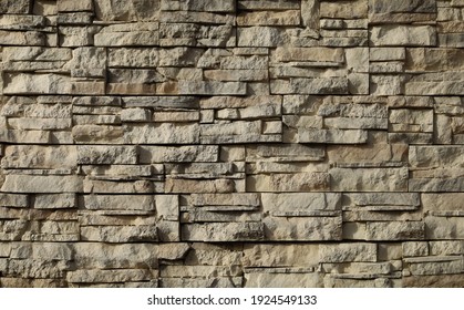Stone cladding wall made of striped stacked slabs of light colors.  Panels for exterior, background and texture.