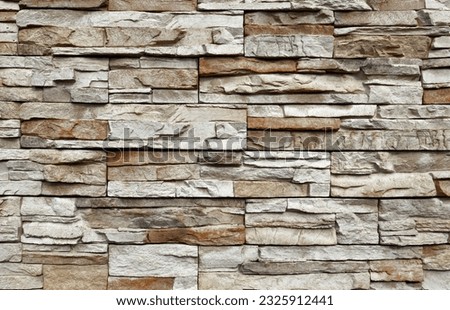 Stone cladding wall made of  striped stacked slabs of  gray and brown rocks. Panels for exterior. Background and texture.