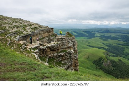 Stone cliffs and cliffs on the green Bermamyt plateau in Karachay-Cherkessia on a cloudy summer day with a hazy haze on the horizon and a space for copy - Shutterstock ID 2253965797