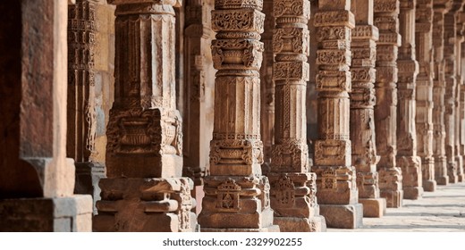 Stone columns with decorative bas relief of Qutb complex in South Delhi, India, close up pillars in ancient ruins of mosque landmark, popular touristic spot in New Delhi, ancient indian architecture