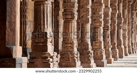 Stone columns with decorative bas relief of Qutb complex in South Delhi, India, close up pillars in ancient ruins of mosque landmark, popular touristic spot in New Delhi, ancient indian architecture