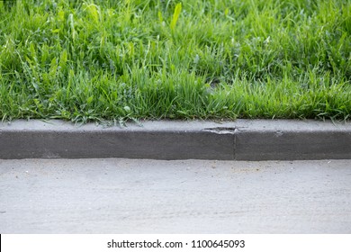 Stone Curb Near The Road. Background, Grass