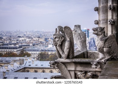 Stone demons gargoyle and chimera/ Paris city on background. View from Notre Dame de Paris, France
