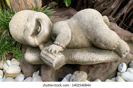 Stone Doll Of Baby With Milk Bottle Lay Down On Bench