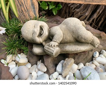 Stone Doll Of Baby With Milk Bottle Lay Down On Bench