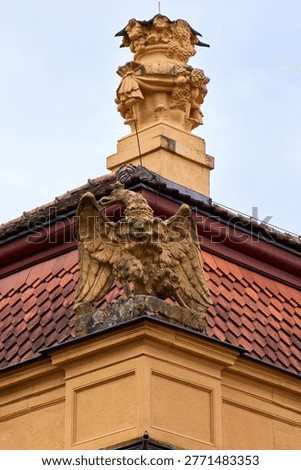 Stone eagle sculpture with spread wings on a building corner, classic baroque architectural detail of historical castle facade in Europe.