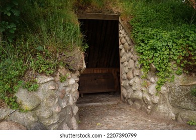 Stone Entrance To An Old Underground House Overgrown With Greenery