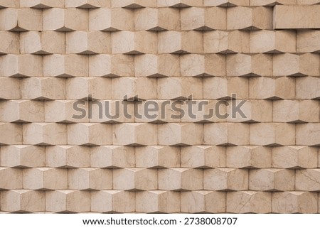 Stone facade features a repeating abstract geometric pattern created by multiple cuboid shapes, forming an intricate three-dimensional texture on the exterior wall