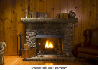 stone fireplace with books on the mantel and the fire blazing inside with natural light