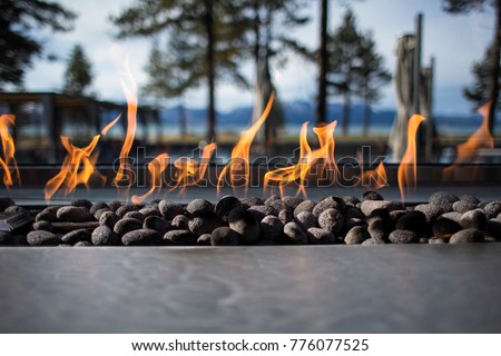 Stone Fireplace Fire Pit with Flames and Trees in Background Outdoors