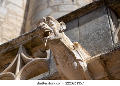 A Stone Gargoyle Protrudes From A Gothic Church Roof