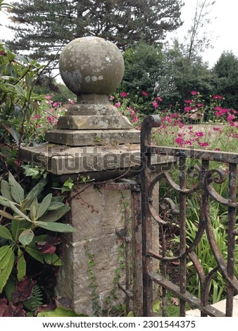 stone gatepost with finial holding a metal garden gate