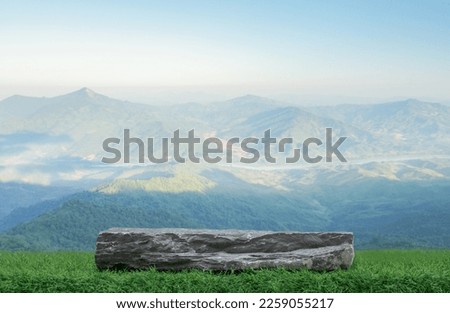 Stone granite podium rock table top on green grass with outdoor mountain scene nature landscape at sunrise background.Natural organic beauty or healthy product placement presentation pedestal display.