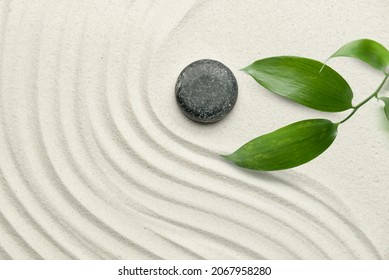 Stone and green branch on sand with lines. Zen concept