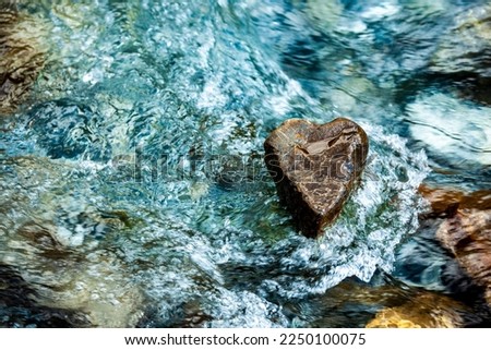 Stone heart in sparkling running water 