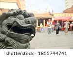 A stone lion against the blurred background of Taipei Xiahai City God Temple.