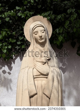 Stone Madonna Sculpture in Leafy Garden