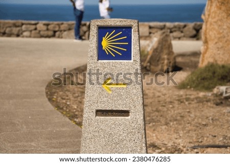 Stone monolith marking the zero kilometer of the road to Santiago, with arrow and shell. Concept pilgrim, road, religion, journey.